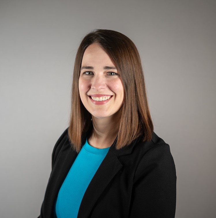 Headshot of Leigh Smith-Vaniz, Title IX Coordinator woman with brown hair, blue shirt, and black blazer